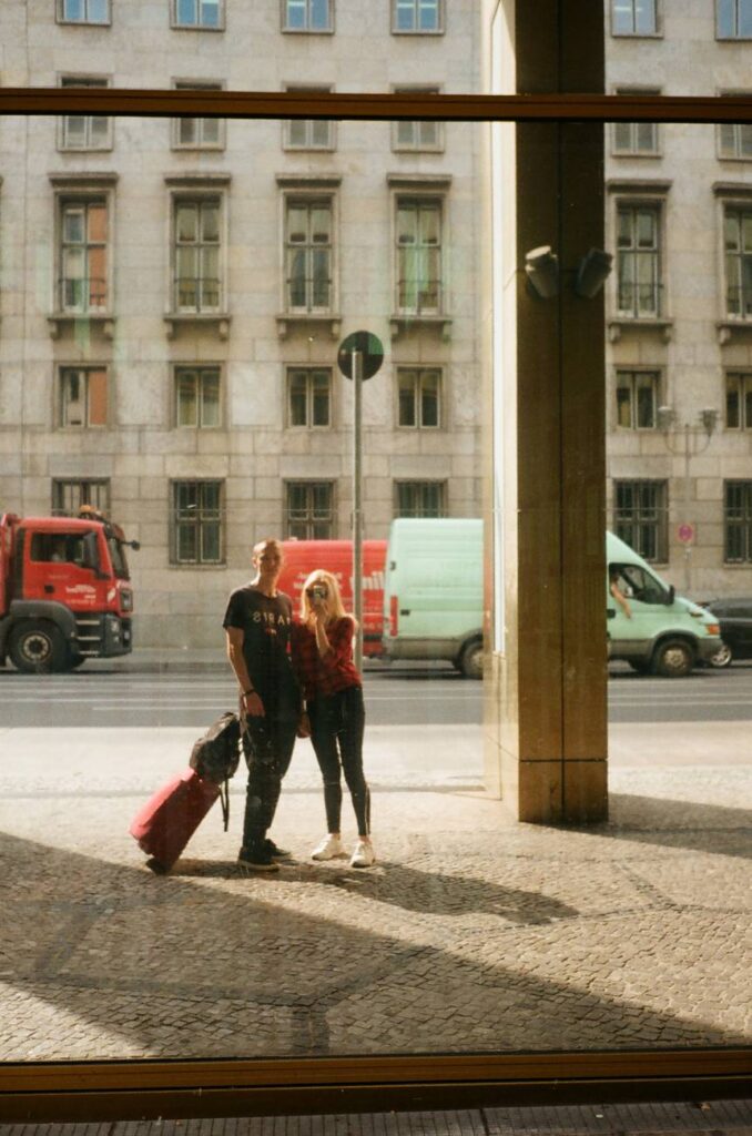 couple of unrecognizable travelers with suitcase on pavement in city