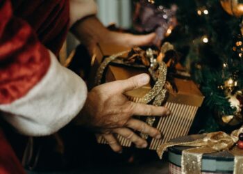 person wearing santa costume holding gold gift box