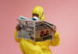 man in yellow protective suit holding a newspaper