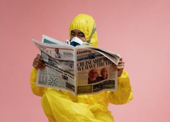 man in yellow protective suit holding a newspaper