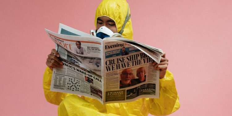 man in yellow protective suit holding a newspaper
