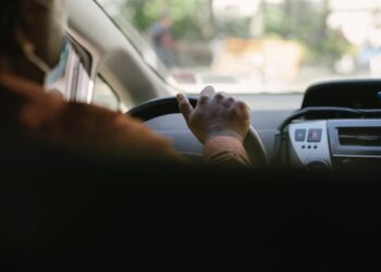 crop ethnic man driving vehicle in town