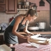 young woman rolling dough for baking in kitchen