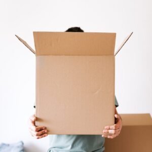 unrecognizable man with carton box in apartment