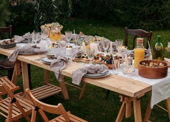 food on brown wooden table with chairs and plates