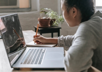 crop student at table with laptop and notebook