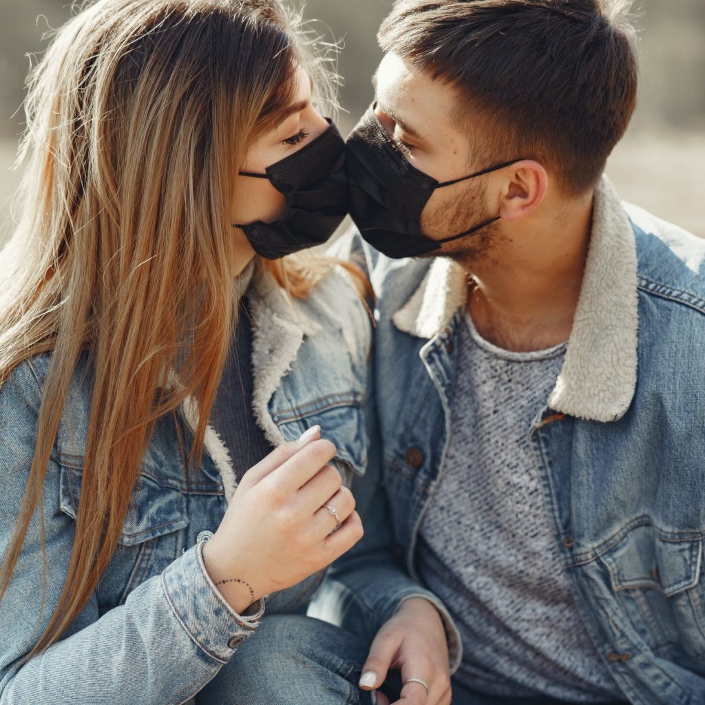 loving young couple kissing while wearing black medical masks