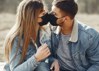 loving young couple kissing while wearing black medical masks