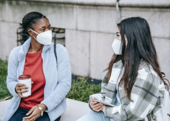 young multiracial ladies chatting on bench in park after studies