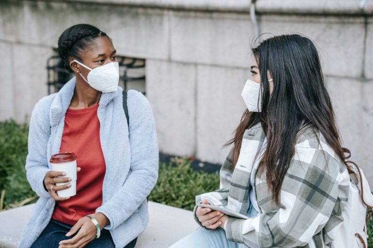 young multiracial ladies chatting on bench in park after studies