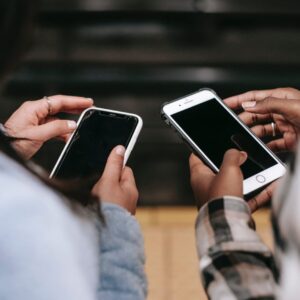crop diverse female partners chatting on smartphones with black screens