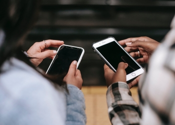 crop diverse female partners chatting on smartphones with black screens