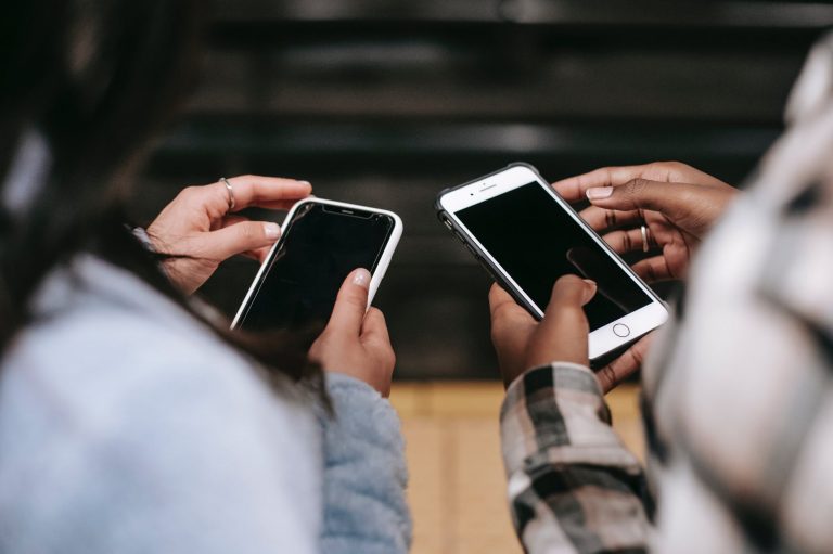crop diverse female partners chatting on smartphones with black screens