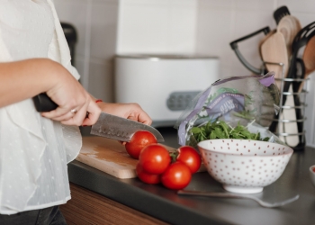 crop woman cutting tomatoes in kitchen