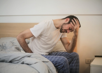 young man in sleepwear suffering from headache in morning
