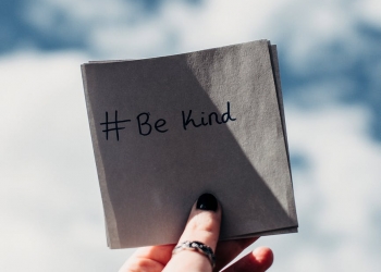 person holding note with be kind text