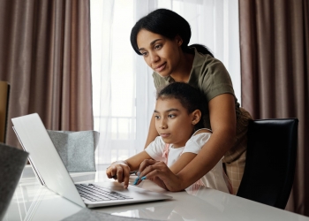 mother helping her daughter use a laptop