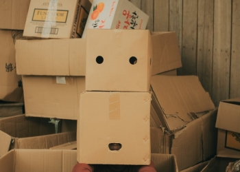 anonymous person with box on head near carton boxes