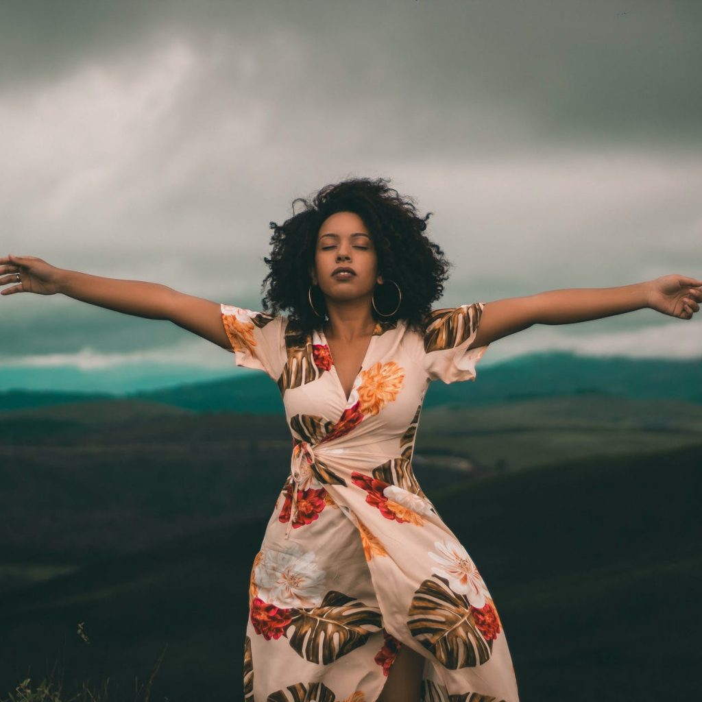 woman in white and red floral dress standing on green grass field