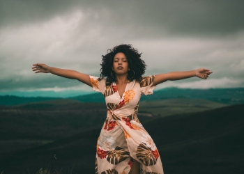 woman in white and red floral dress standing on green grass field