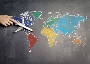 person with toy airplane on world map