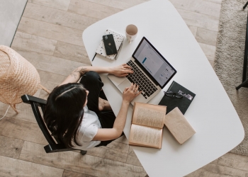 young lady typing on keyboard of laptop in living room