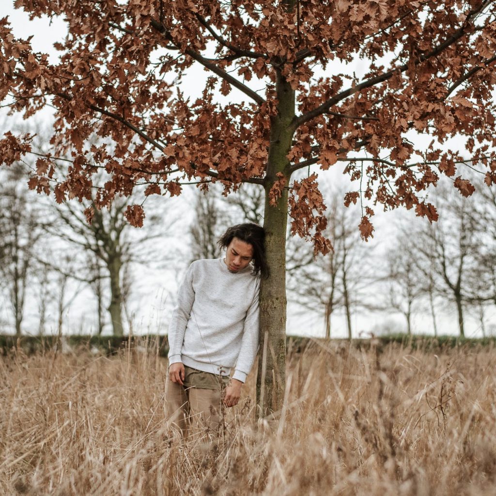 man leaning against a tree