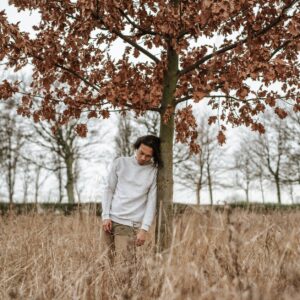 man leaning against a tree