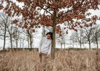 man leaning against a tree