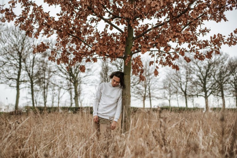 man leaning against a tree