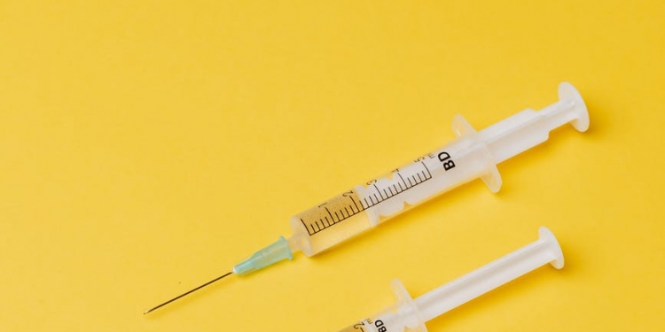 syringes with medical drugs on yellow background
