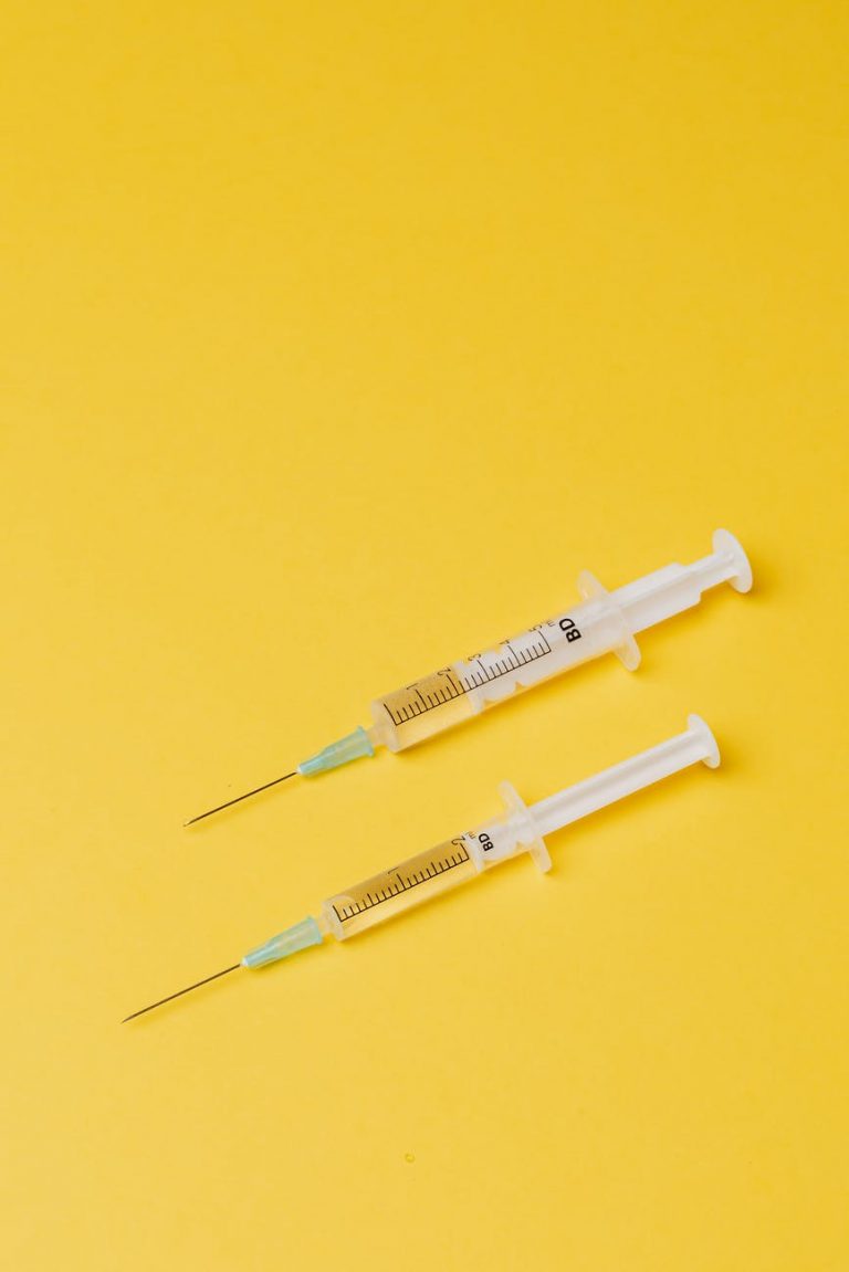 syringes with medical drugs on yellow background