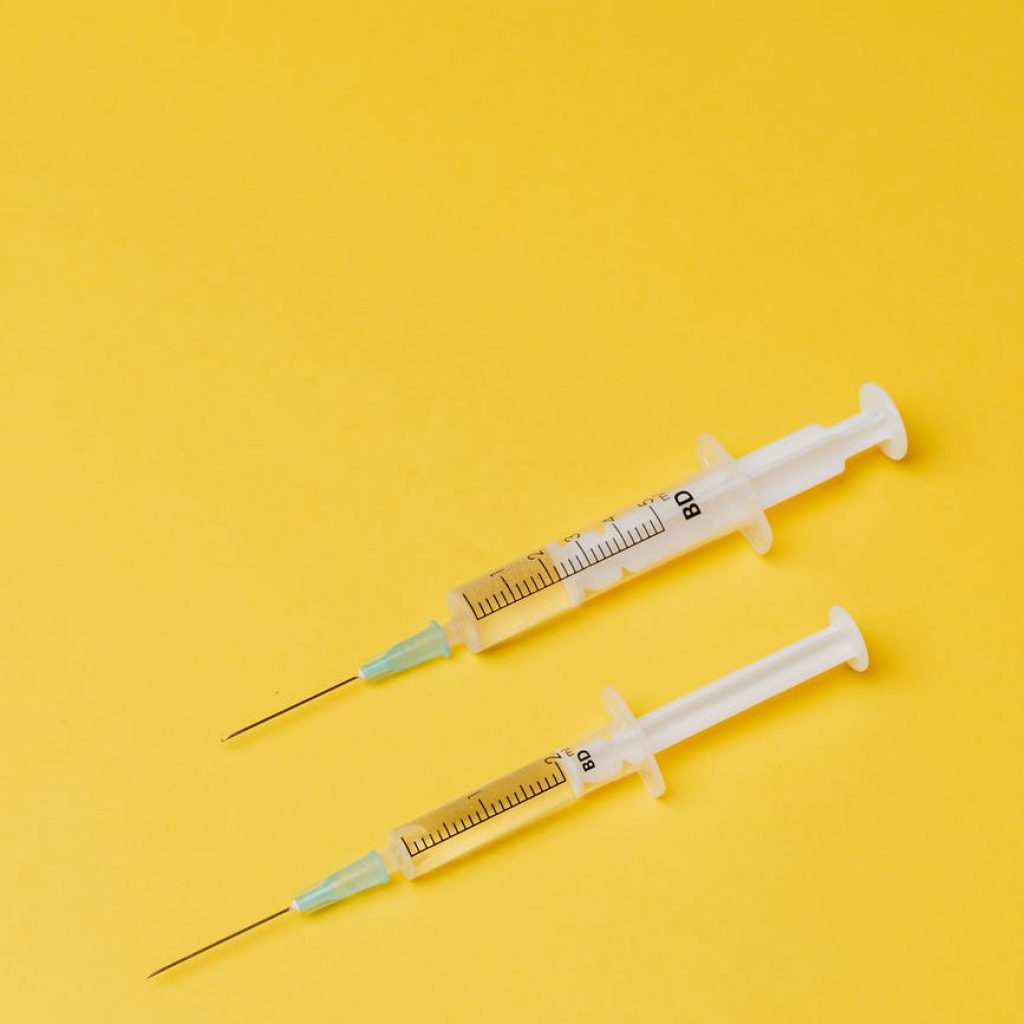 syringes with medical drugs on yellow background