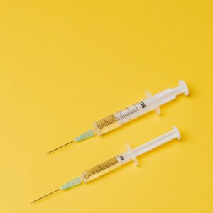 syringes with medical drugs on yellow background
