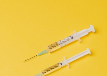 syringes with medical drugs on yellow background