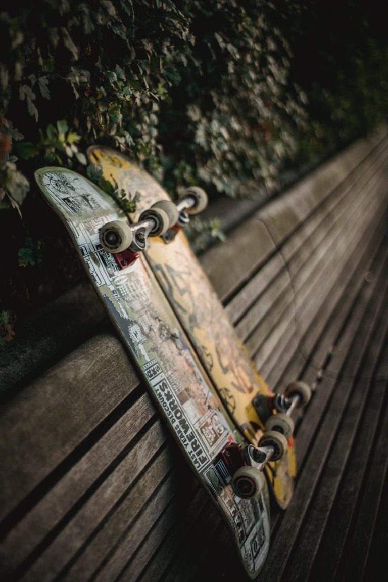 skateboards placed on wooden bench in green park