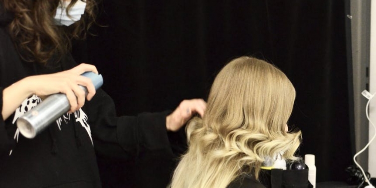 hairdresser making hairdo for client in dressing room