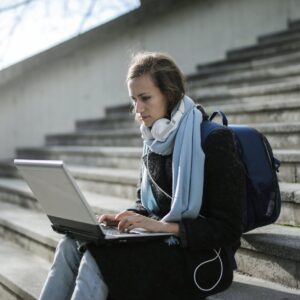 woman sitting on concrete stairs using laptop