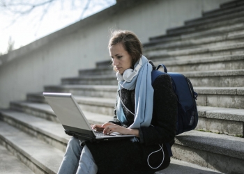 woman sitting on concrete stairs using laptop