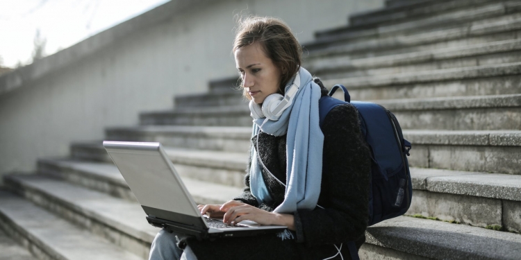woman sitting on concrete stairs using laptop