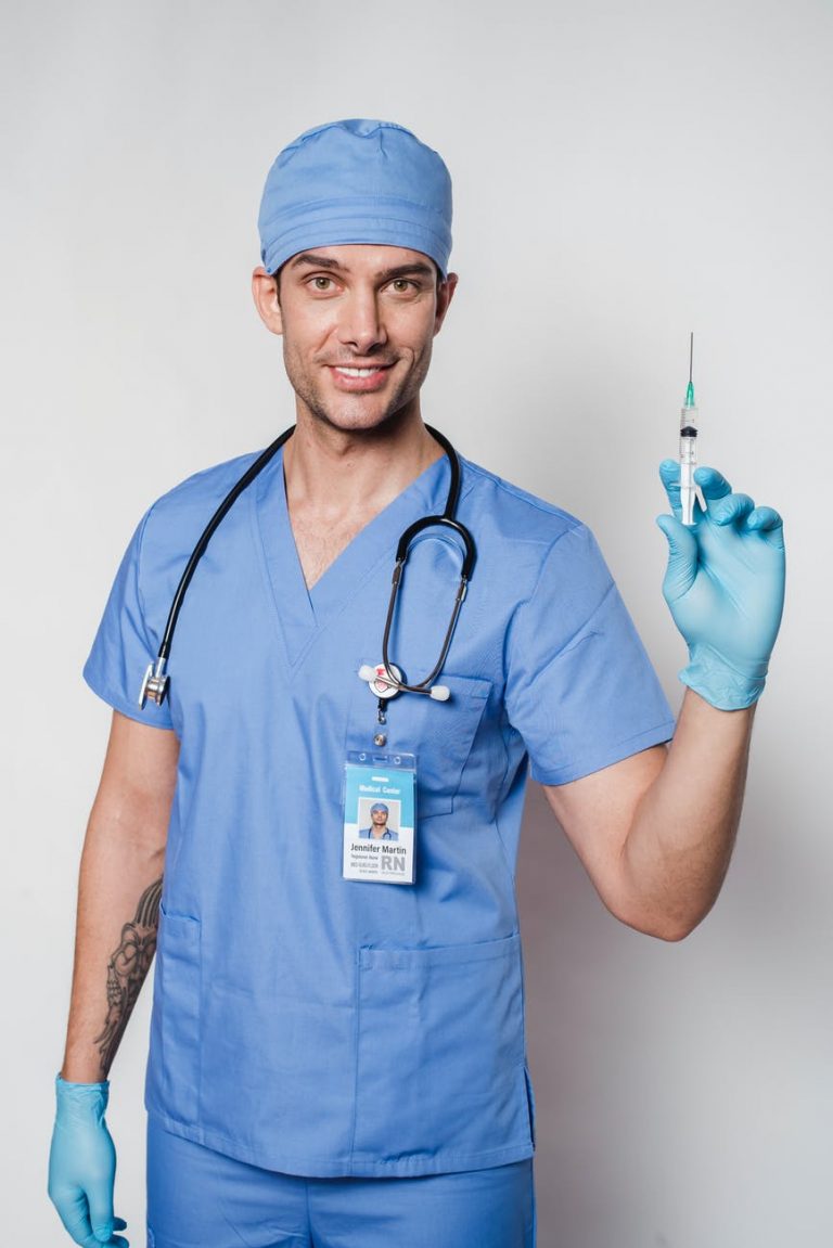 cheerful tattooed doctor with syringe in uniform