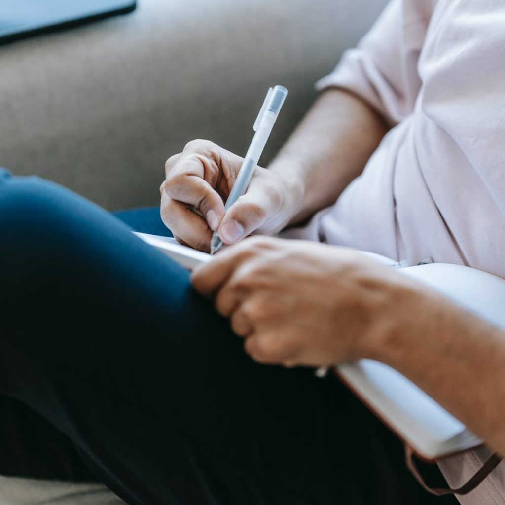crop unrecognizable person writing in diary