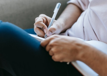 crop unrecognizable person writing in diary