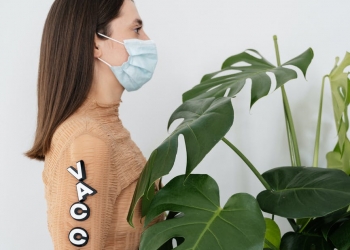 woman in brown sweater standing beside green plant