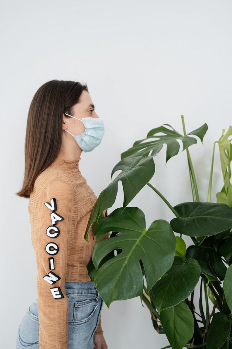 woman in brown sweater standing beside green plant