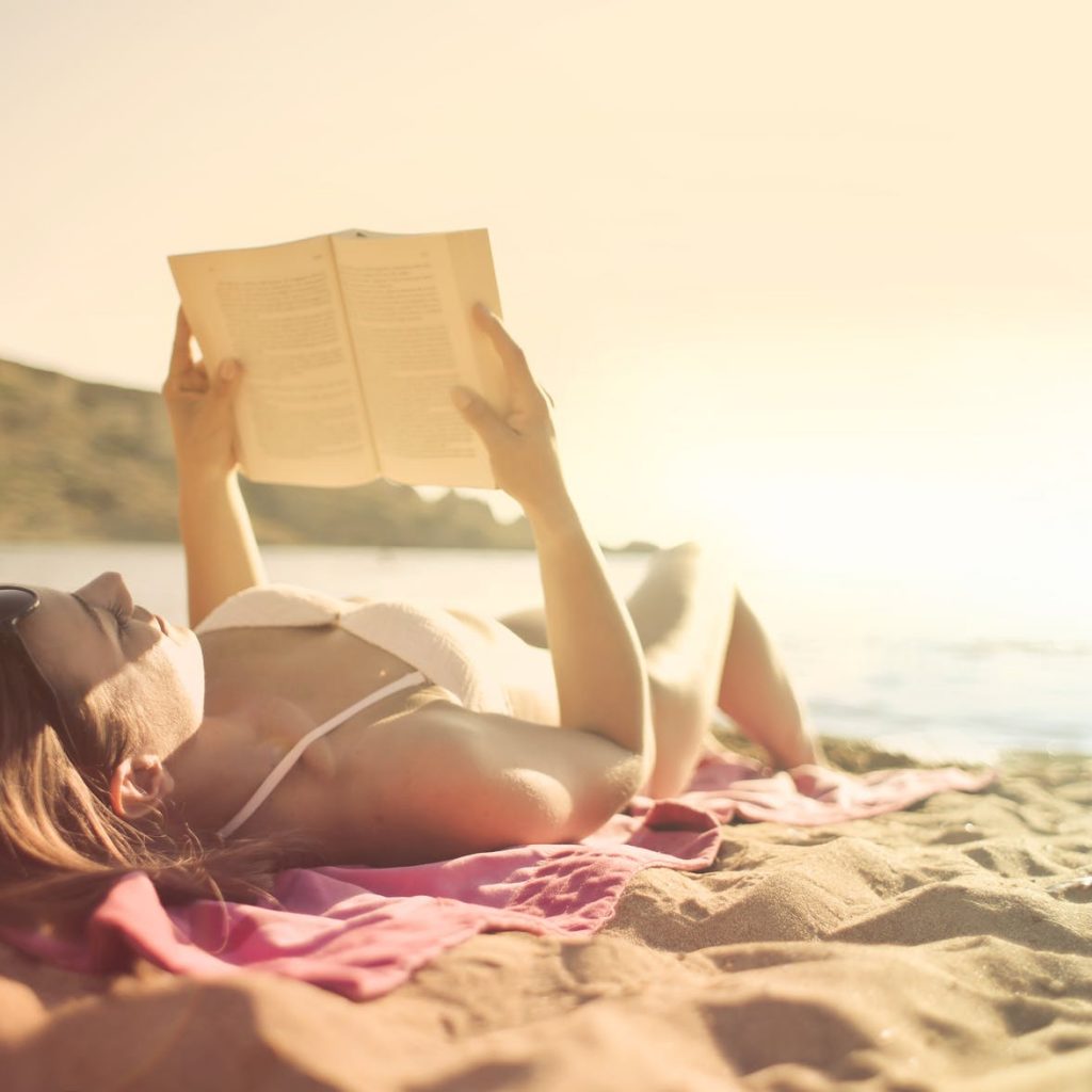 woman lying on beach reading book