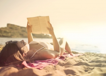 woman lying on beach reading book