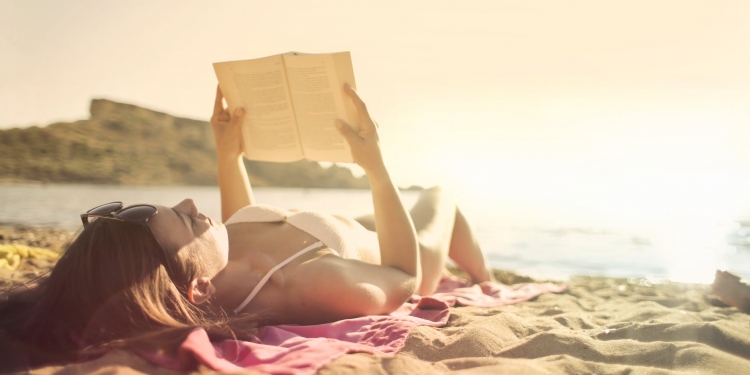woman lying on beach reading book