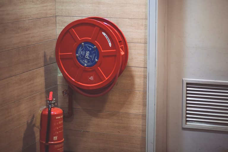 red fire extinguisher below hose reel