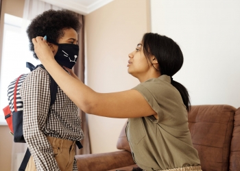 mother putting a face mask on her son